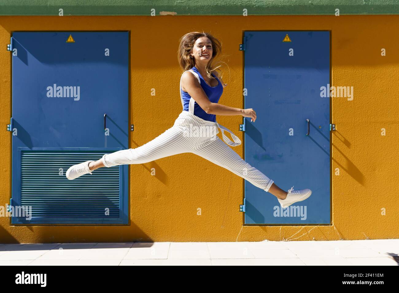 Happy young woman jumping in urban background. Gen Z girl. Happy young woman jumping in urban background Stock Photo