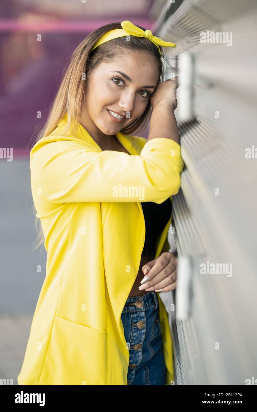 Young woman wearing a yellow jacket and headband in urban background ...