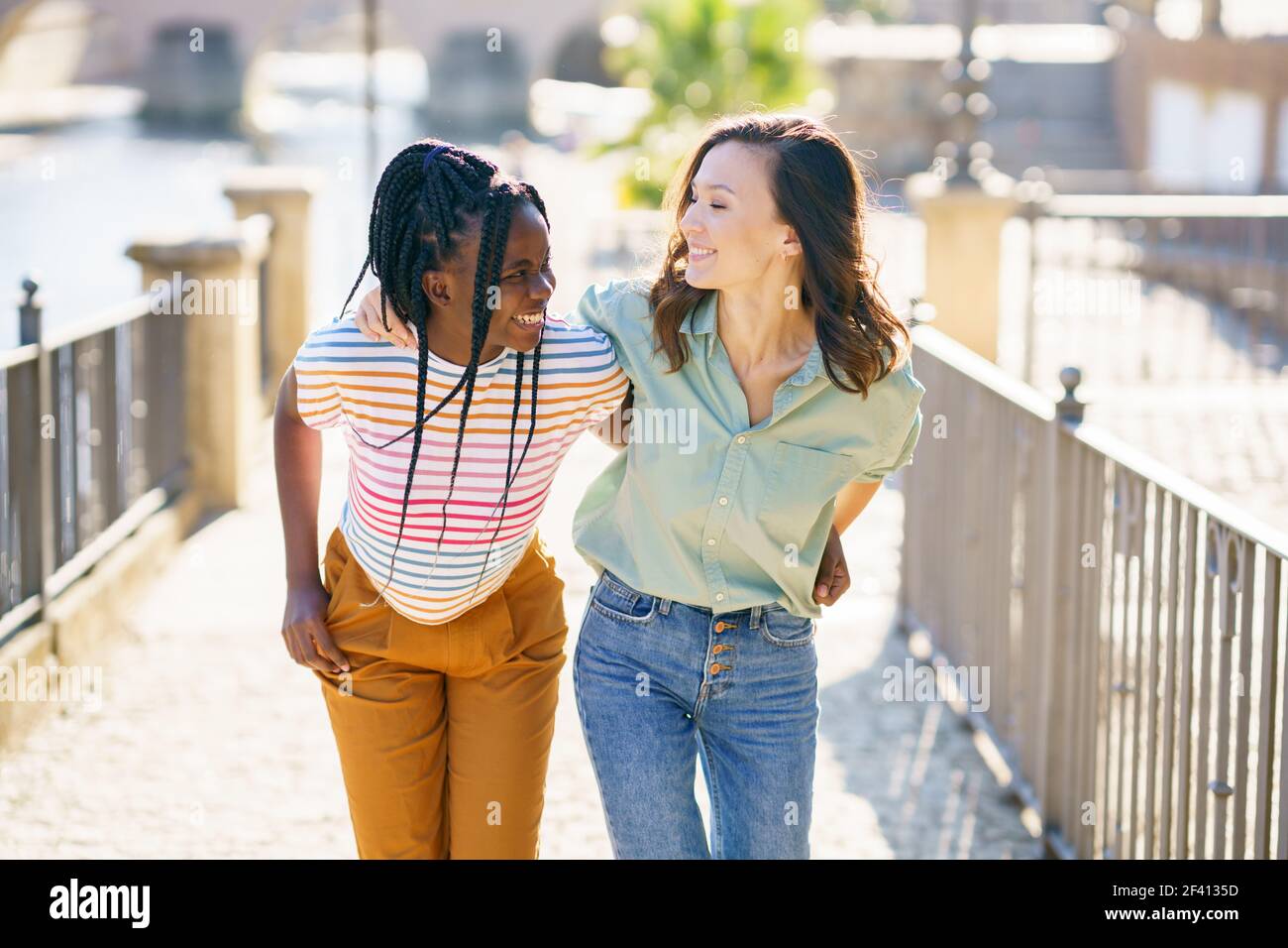 Two friends walking together on the street. Multiethnic women.. Two Multiethnic women walking together on the street. Stock Photo