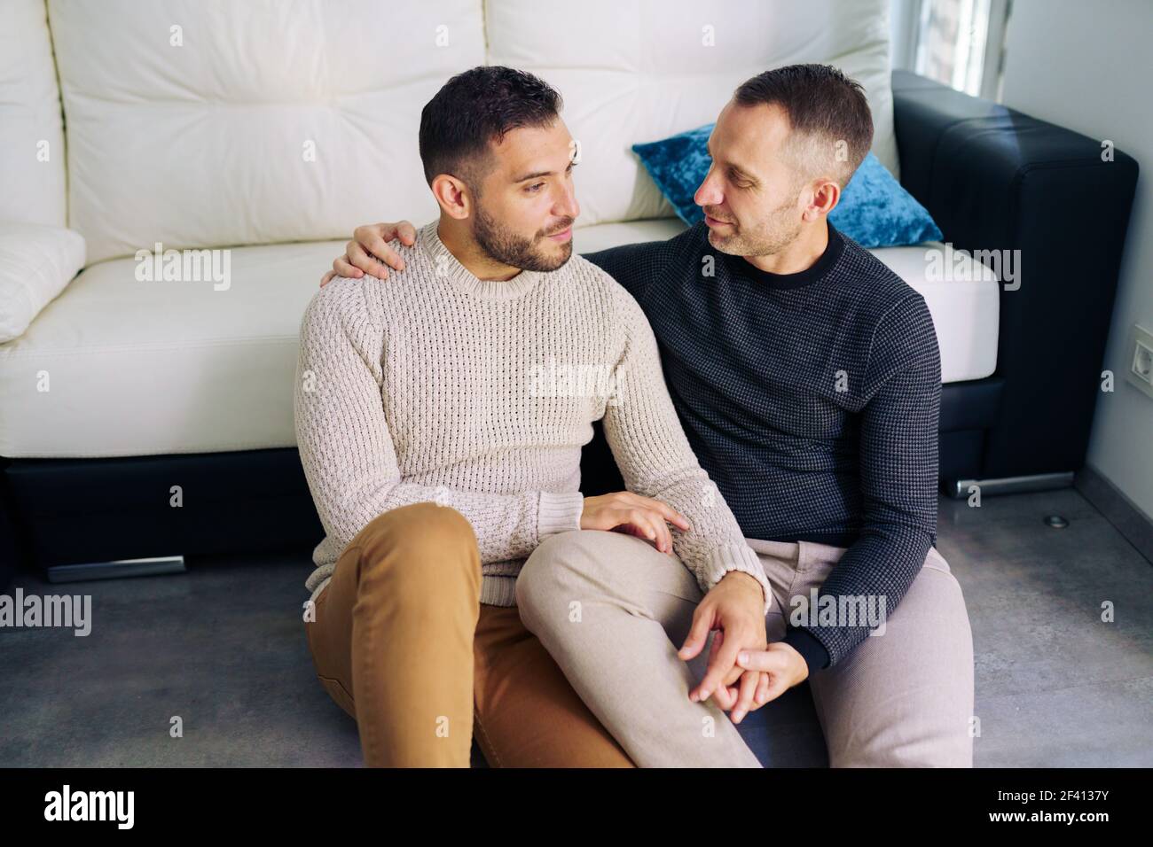 Gay Couple Sitting Near The Couch At Home In A Romantic Moment Homosexual Relationship Concept Gay Couple Sitting Near The Couch At Home In A Romantic Moment 2F4137Y