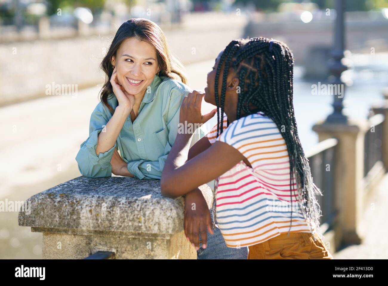 Two friends talking together on the street. Multiethnic women.. Two Multiethnic women talking together on the street. Stock Photo