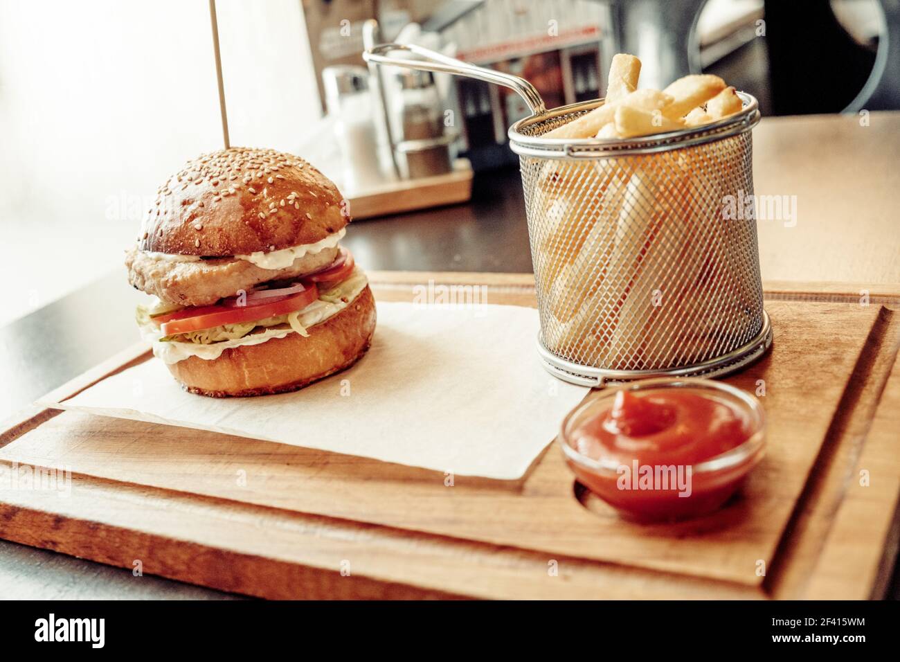 Angle View Of Craft burger , tomato souse and french fries on wooden plate. Craft burger and french fries on wooden plate Stock Photo