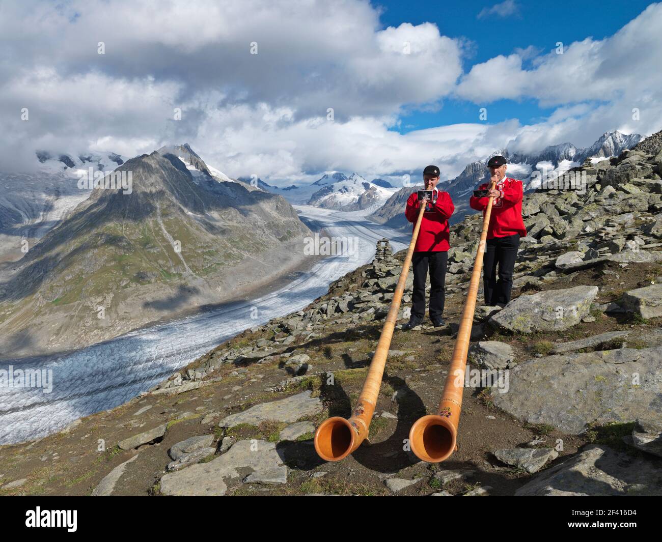 Switzerland, Goms Region, Aletsch, the Aletsch Glacier with two Swiss musicians playing the alpenhorn music instrument Stock Photo