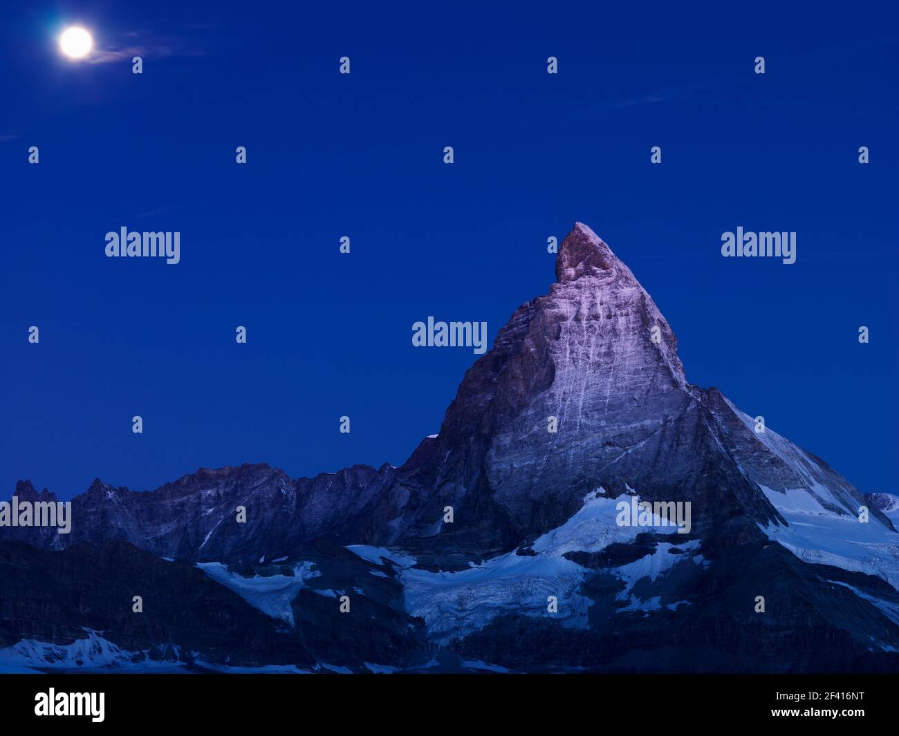 moon setting over the Matterhorn at dawn Stock Photo