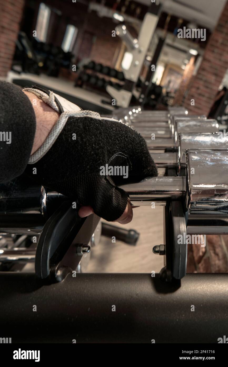 Man Taking One Of Shiny Steel Dumbbells In Gym Stock Photo