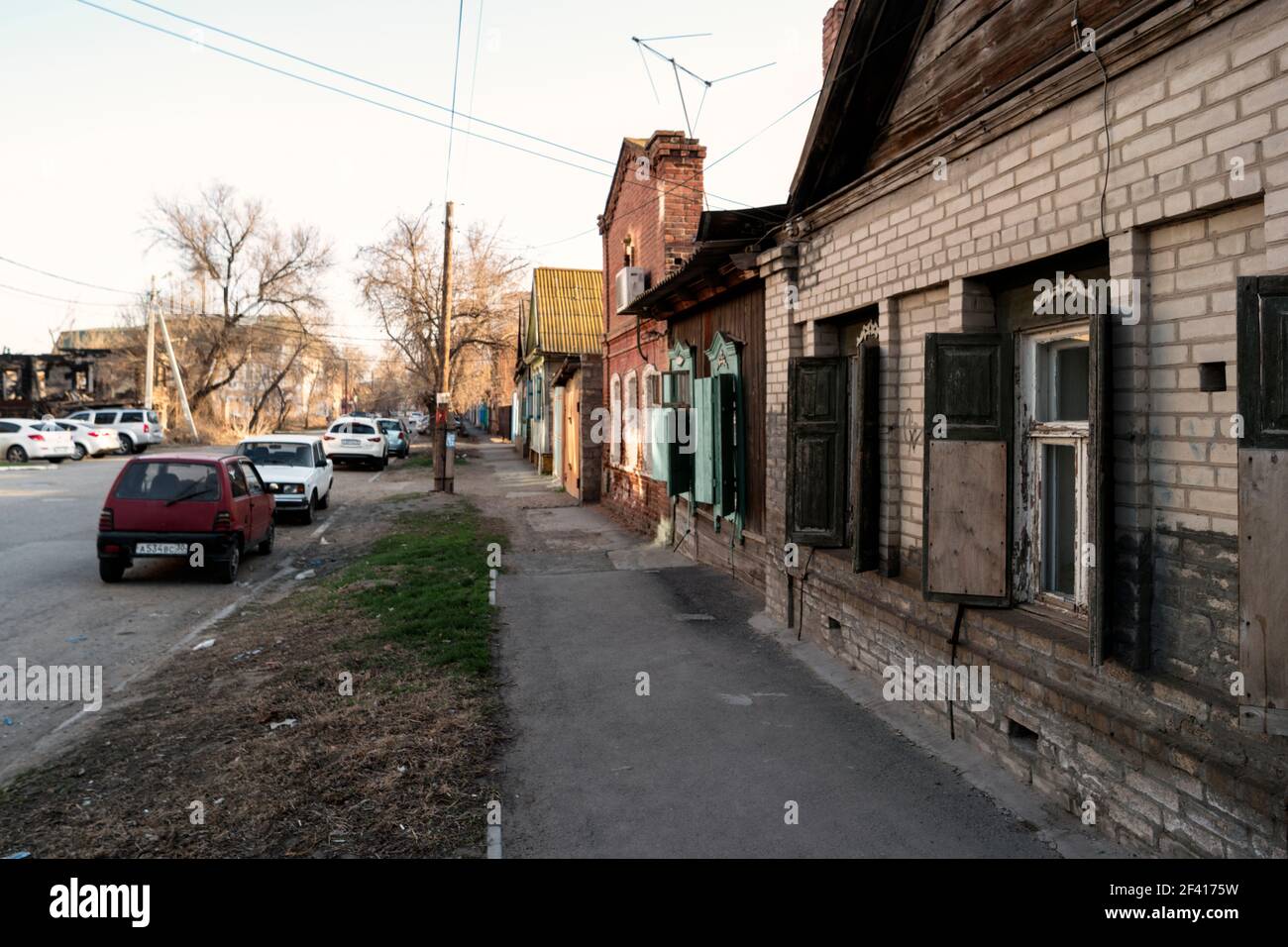 Astrakhan, Russia 12 of April 2018: In The Street Of Astrakhan In Sunny Spring Day With Expensive Cars Parked About Old Slum Houses. Astrakhan, Russia 12 of April 2018: In The Street Of Astrakhan In Sunny Spring Day With Cars Parked About Old Houses Stock Photo