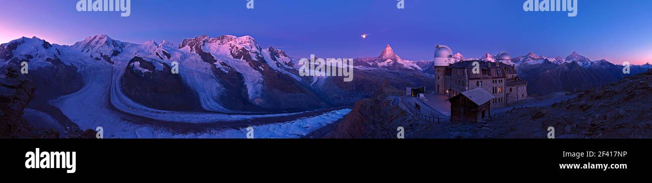 First morning light and moon setting at dawn over the Matterhorn, the Gorner Glacier and Kulmhotel at the Gornergrat Stock Photo