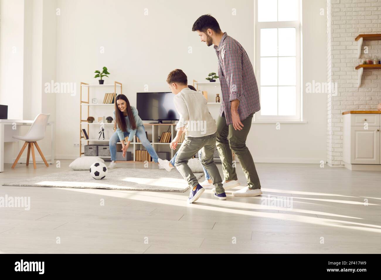 Mother trying to catch soccer ball having fun with adorable family at home Stock Photo