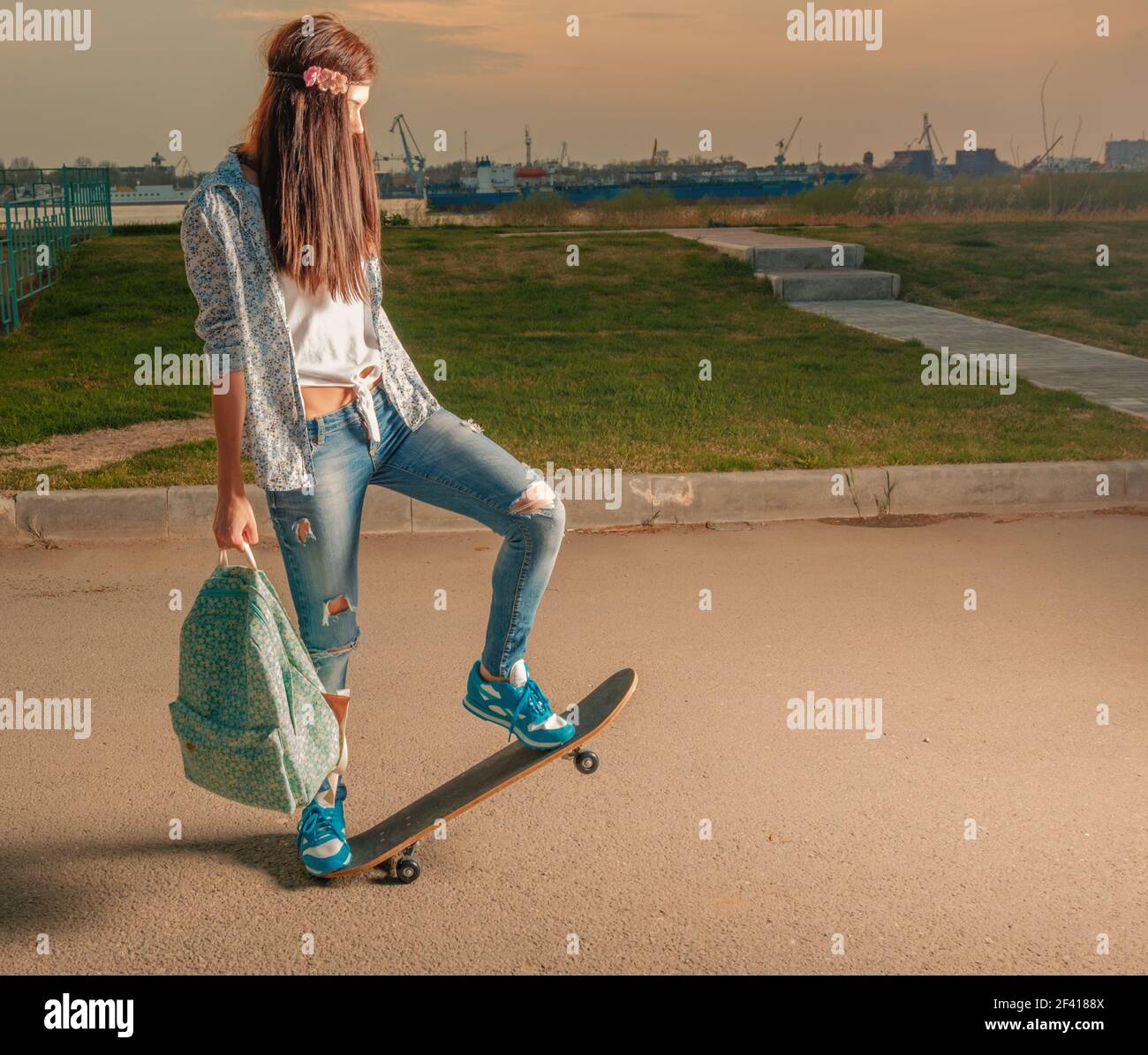 Hipster girl on skateboard with backpack in her hands. Hipster girl on skateboard with backpack Stock Photo