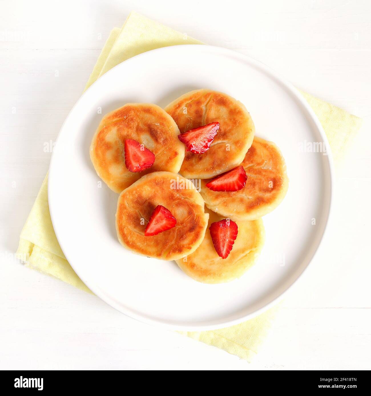 Cottage cheese pancakes with strawberry, syrniki on white plate. Top view, flat lay Stock Photo