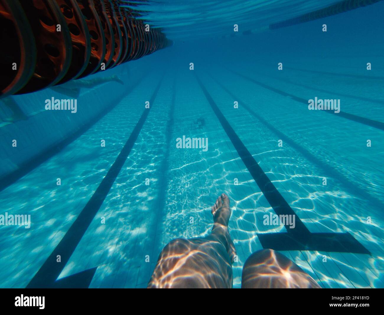 Womans legs underwater in swimming pool near pools bottom. Womans legs