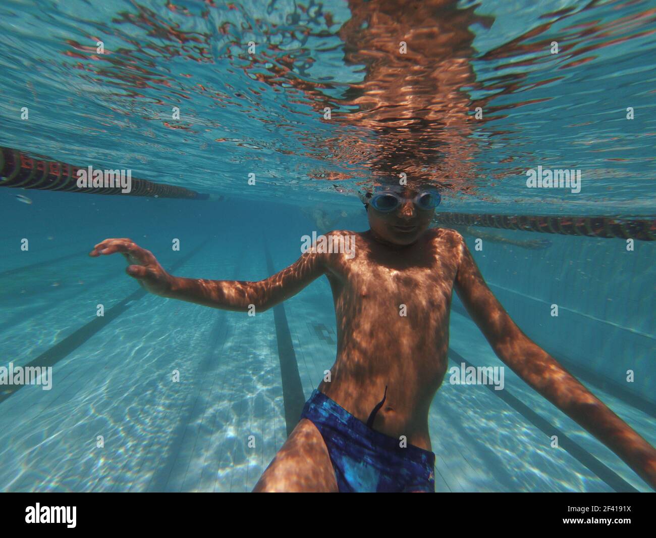 Boy swimming underwater in swimming pool in goggles. Boy swimming