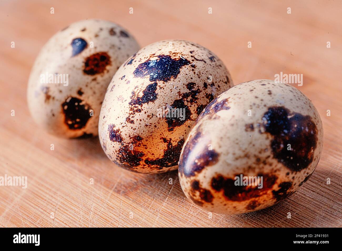 Three quail eggs on wooden board in row. Three quail eggs on wooden board Stock Photo