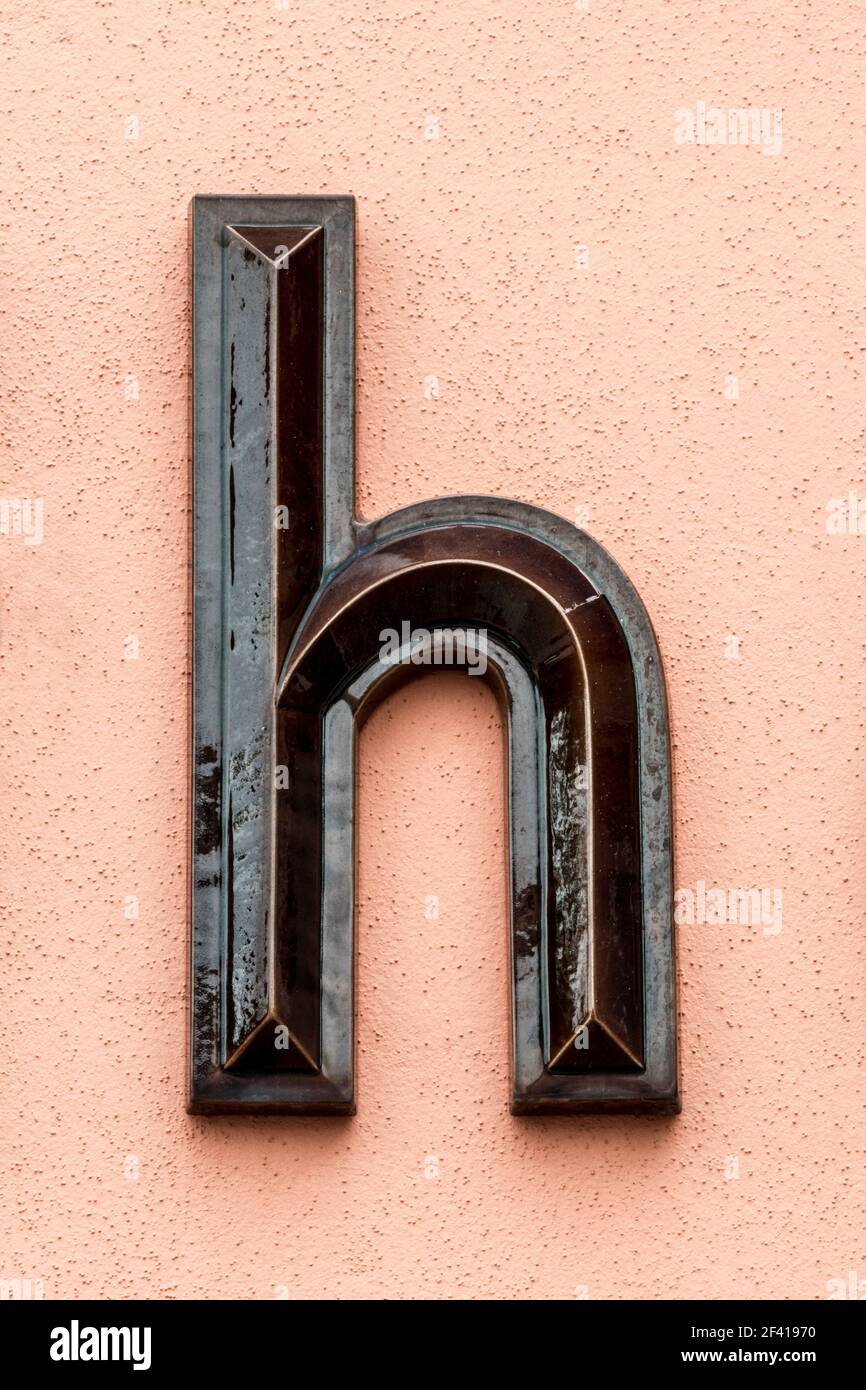 Dark brown glazed letter h on a bright orange wall Stock Photo