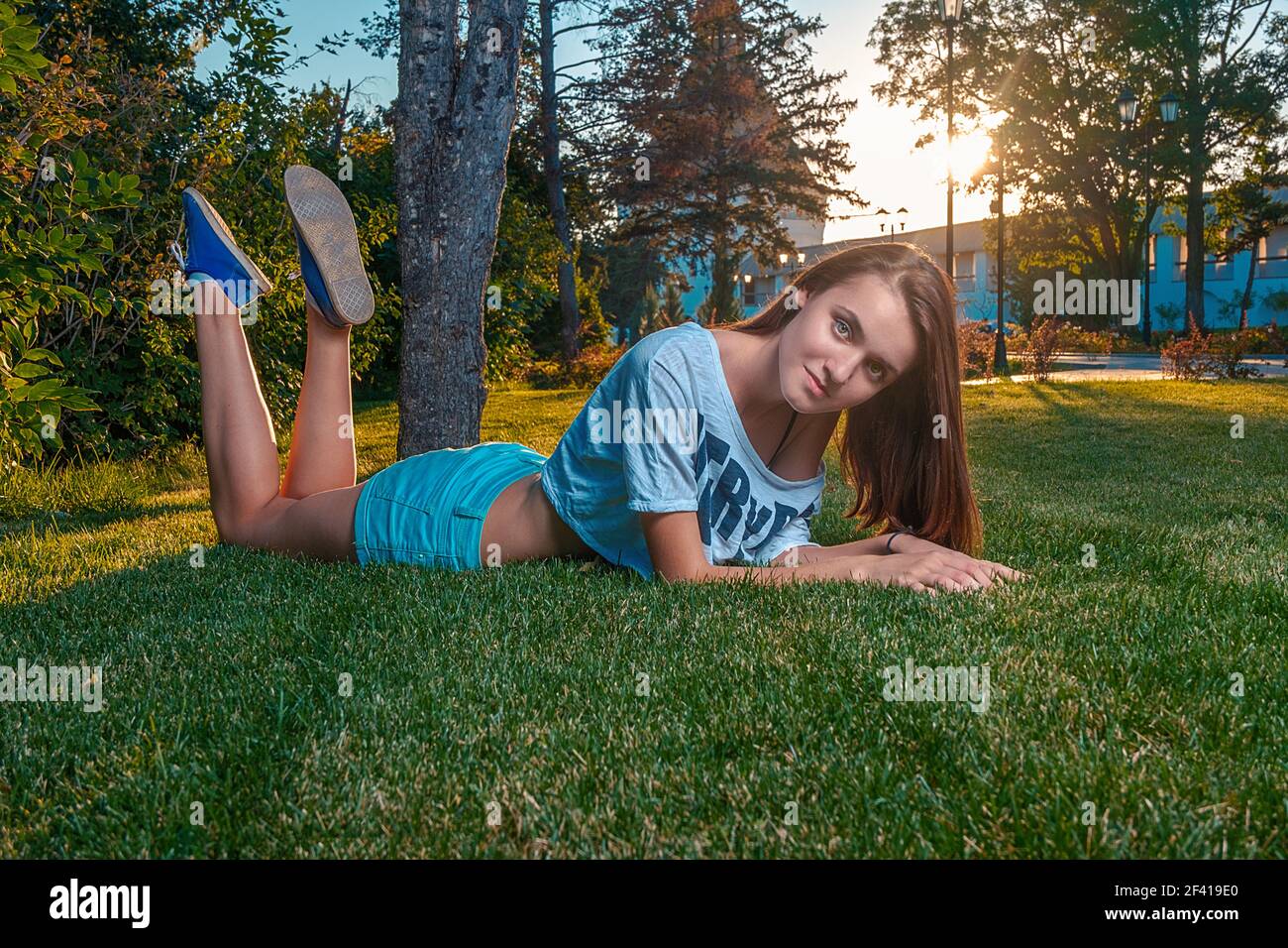 Ginger haired girl lying on grass and looking in camera with pretty smile on her face, copyspace on foreground grass. Ginger haired girl lying on grass and looking in camera with pretty smile on her face, copyspace on grass Stock Photo
