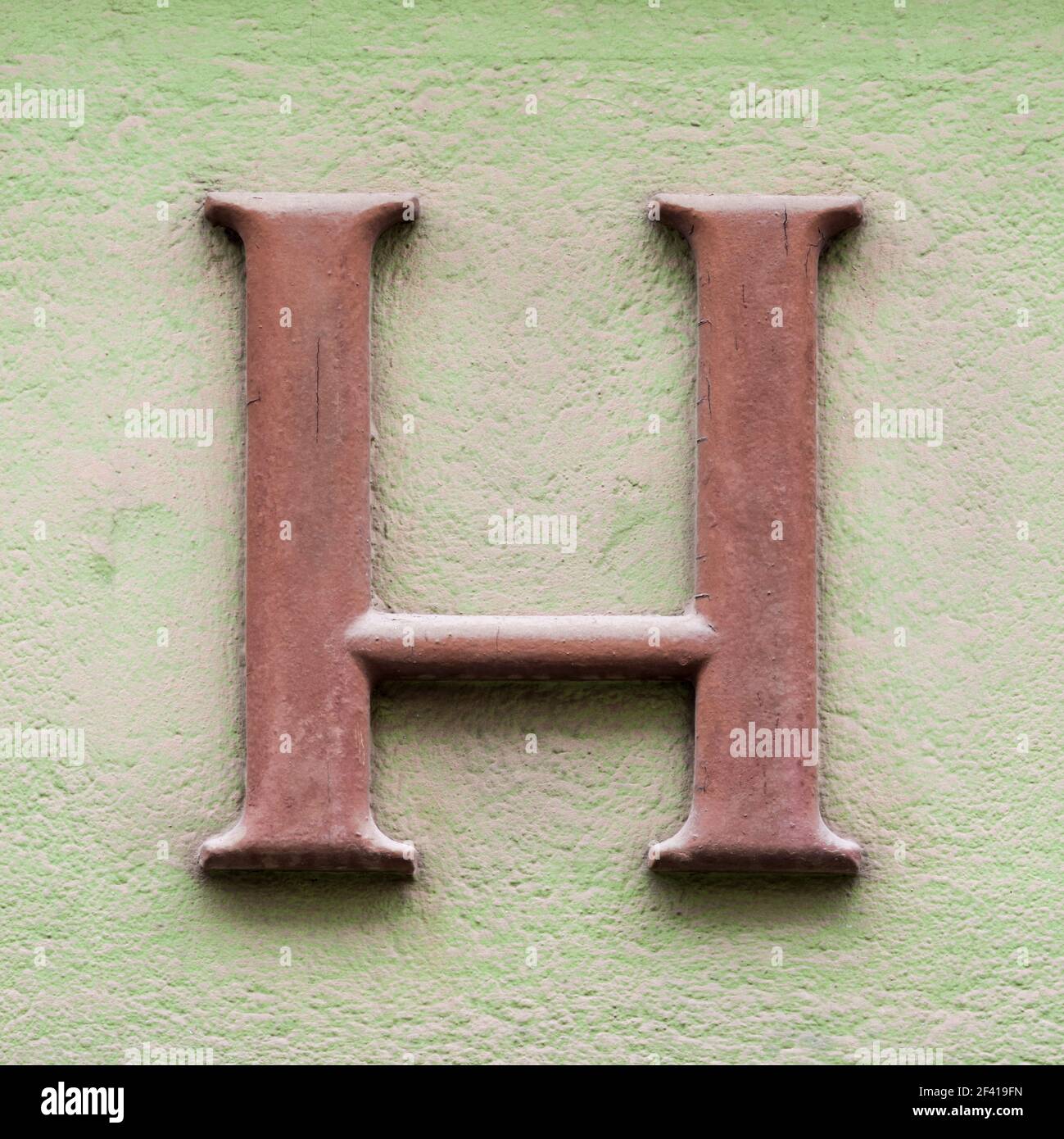 Brown letter E with serifs on green house wall Stock Photo