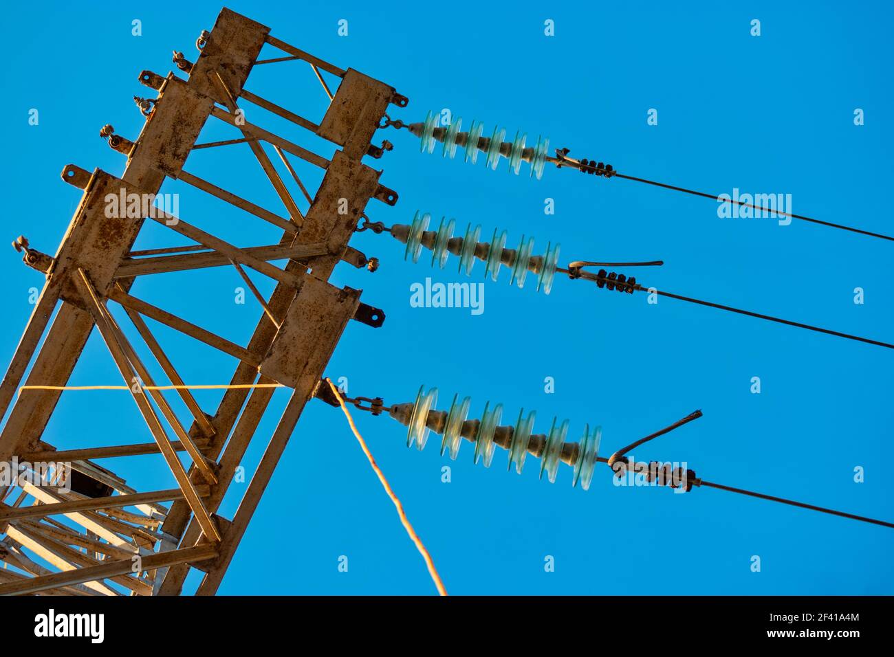 High voltage transmission power tower with glass insulators and wires against blue sky. High voltage transmission power tower with glass insulators and wires against sky Stock Photo