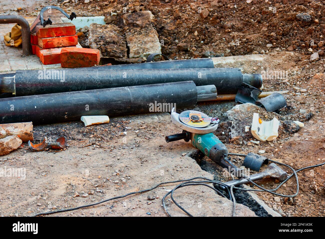 Construction Site with angle drive grinder lying in the dirt and bunch of waterpipes on the ground. Construction Site with angle drive grinder lying in the dirt and bunch of waterpipes Stock Photo