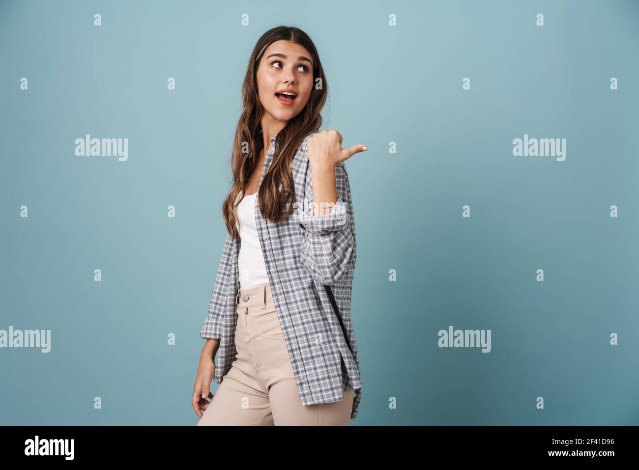 Excited beautiful girl looking and pointing finger aside isolated over ...