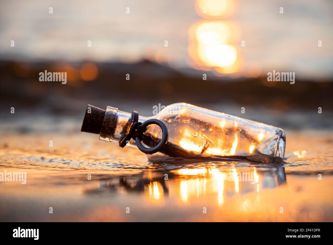 Message in the bottle against the Sun setting down Stock Photo