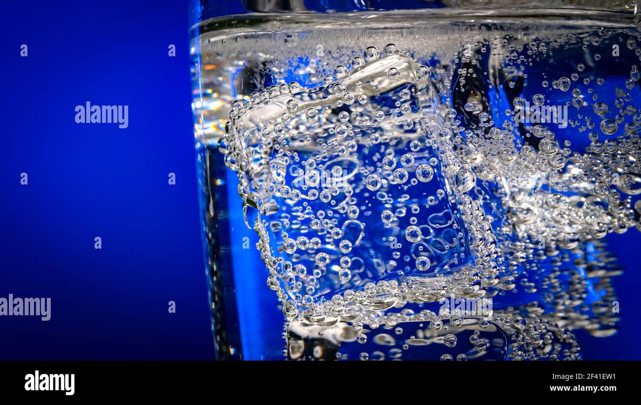 Glass of water with ice on a dark blue background Stock Photo - Alamy