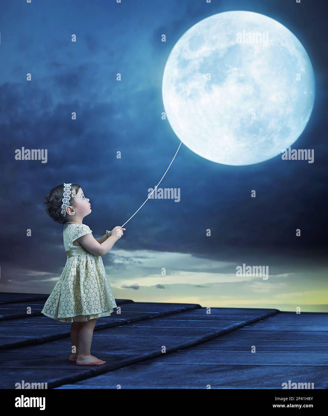 Conceptual image of a cute baby holding a moon-balloon Stock Photo