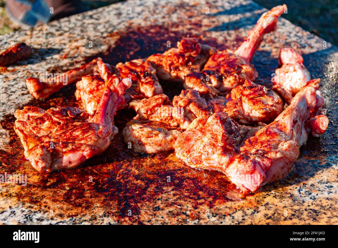 meat of young lamb on the bone is fried on marble slab. Picnic in nature. delicious juicy grilled lamb meat. kitchen in nature. selective focus. Stock Photo