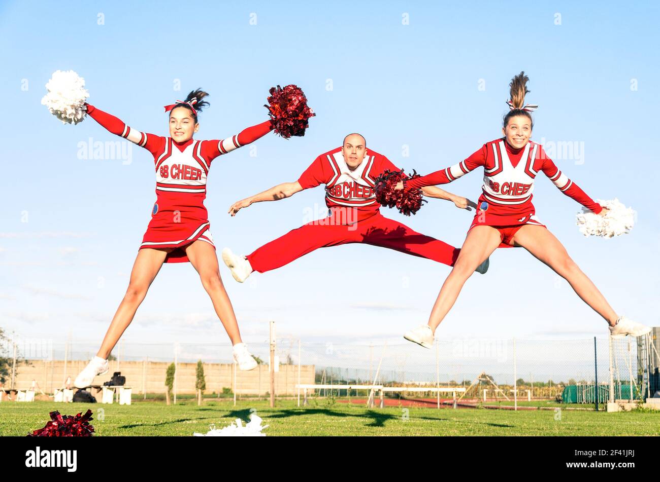 Cheerleaders team with male coach performing a synchronized jump Stock Photo