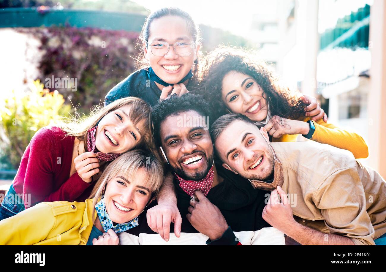 Multiracial people taking selfie with opened face mask outdoors - Happy life style concept with young students having fun together after lockdown Stock Photo