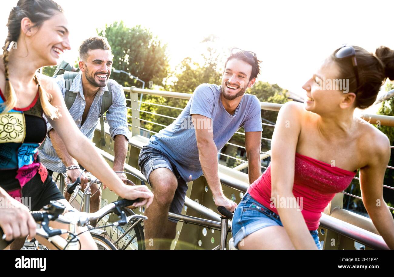 Happy millenial friends having fun riding bicycle in city park - Friendship concept with young millennial people students biking together Stock Photo