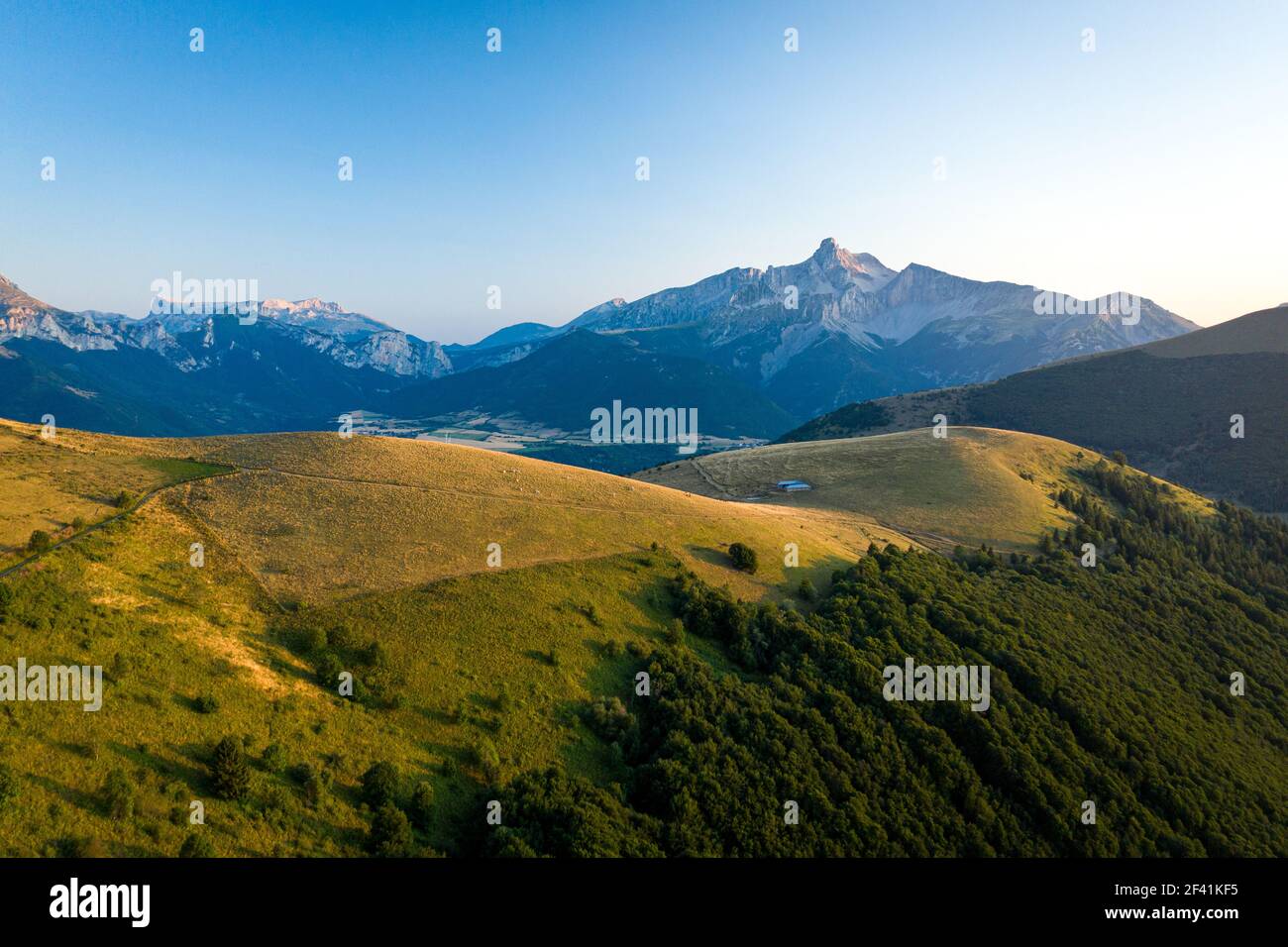 Stunning grassy hill in front of the mountain landscape Stock Photo