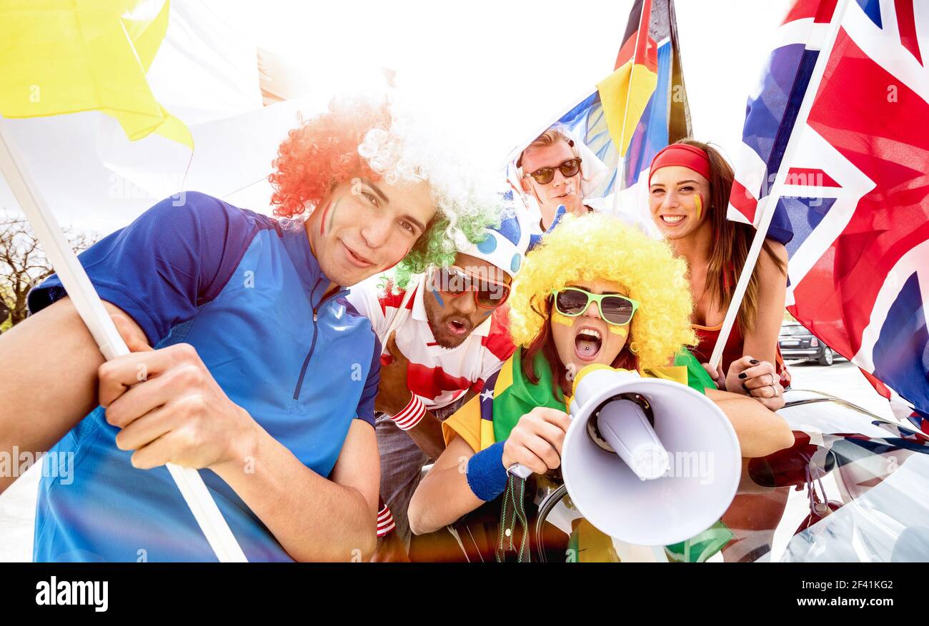 Football supporter fans friends cheering after soccer cup match hanging around with car and flags - Young people group with multicolored t-shirts Stock Photo