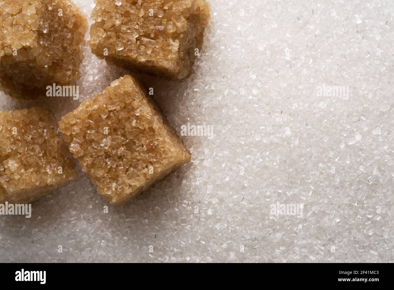 White refined sugar granules and brown sugar cubes close-up. Food background. Stock Photo
