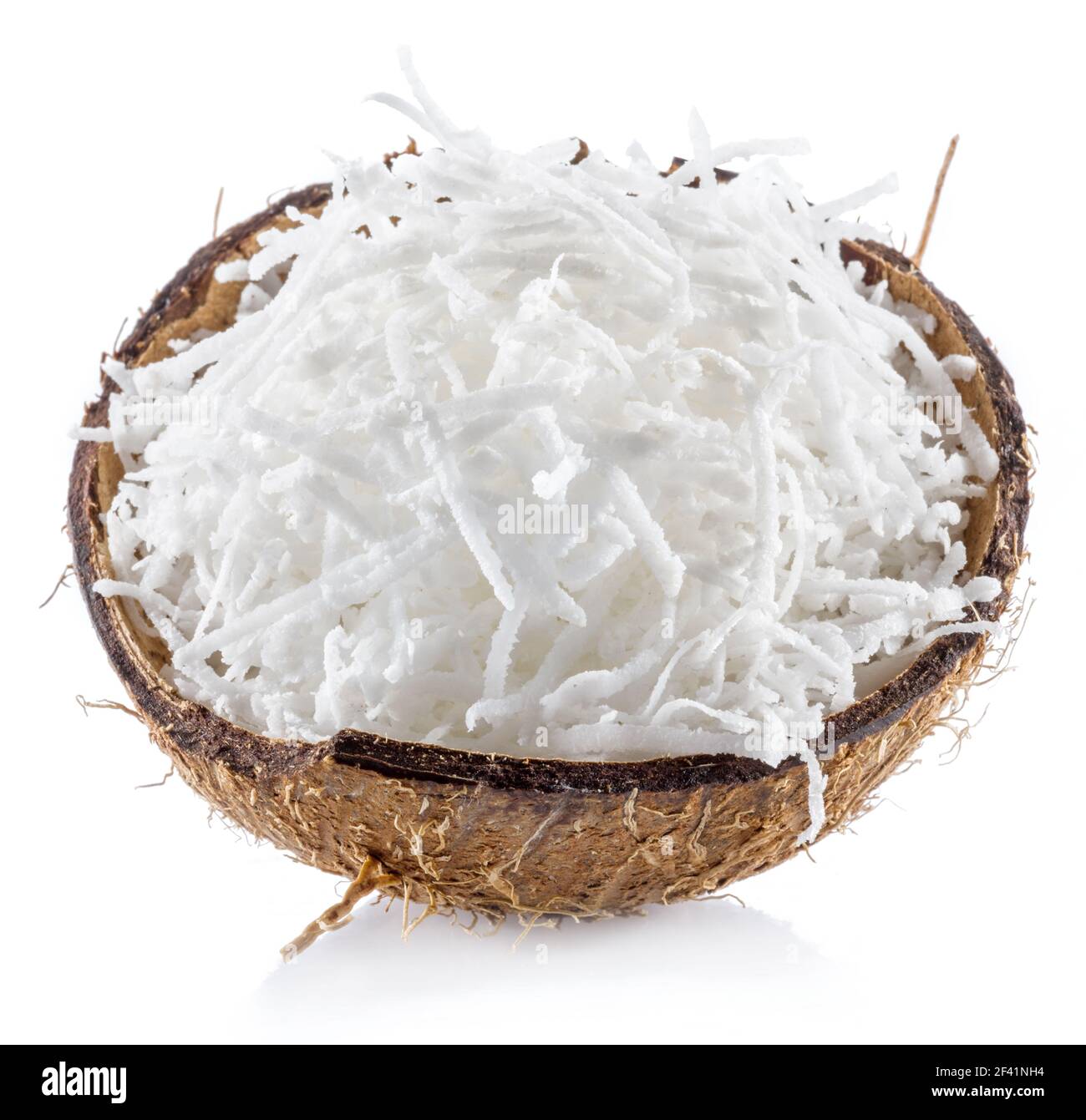 Shredded coconut flakes in the piece of coconut shell isolated on white background. Stock Photo