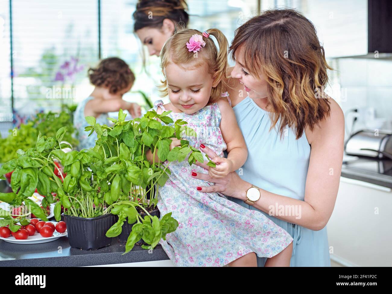 Young mothers with their beloved children in the bright, summer kitchen Stock Photo