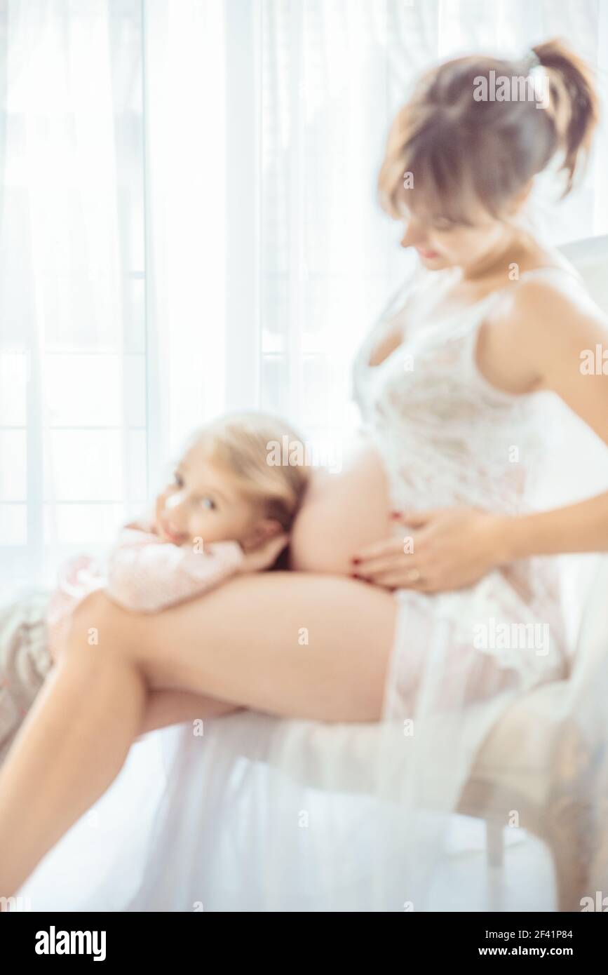 Charming, little daughter touching a pregnant mother&rsquo;s belly Stock Photo