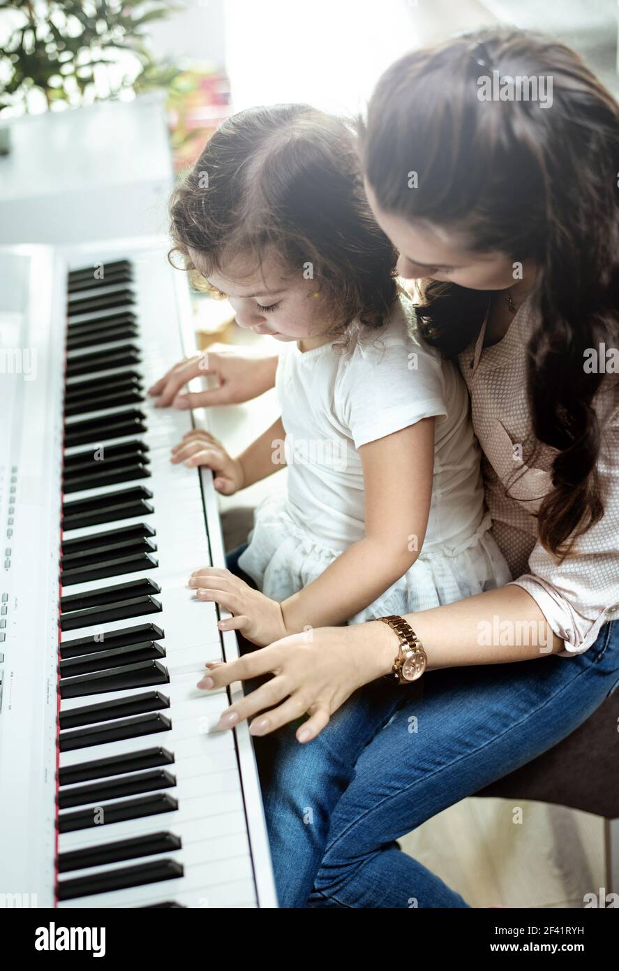 Young mother playing piano with her little daughter Stock Photo - Alamy