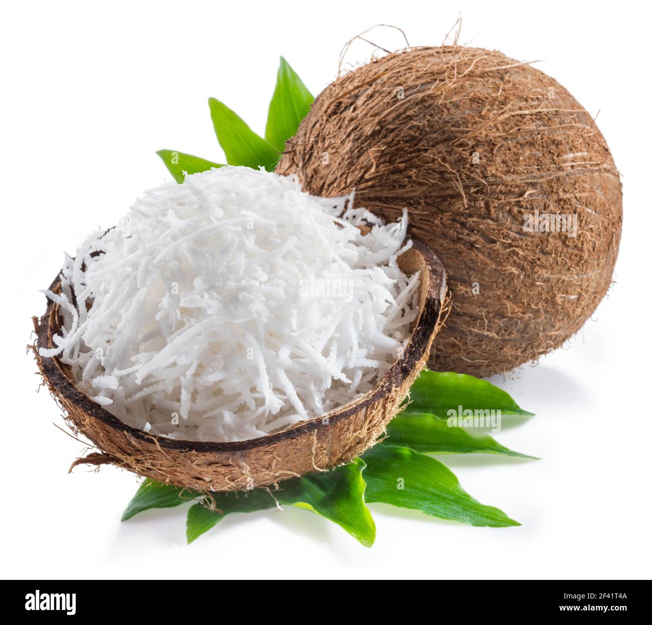 Cracked coconut fruit with white shredded flesh and whole coconut isolated on white background. Stock Photo