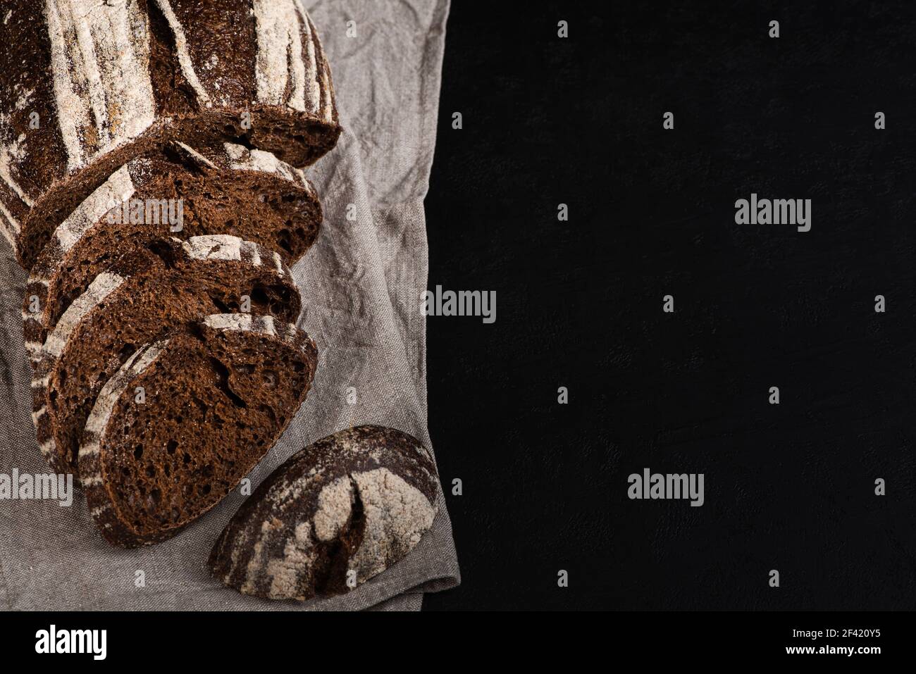 Sliced rye bread on black background. Rustic artisan bread. Copy space Stock Photo