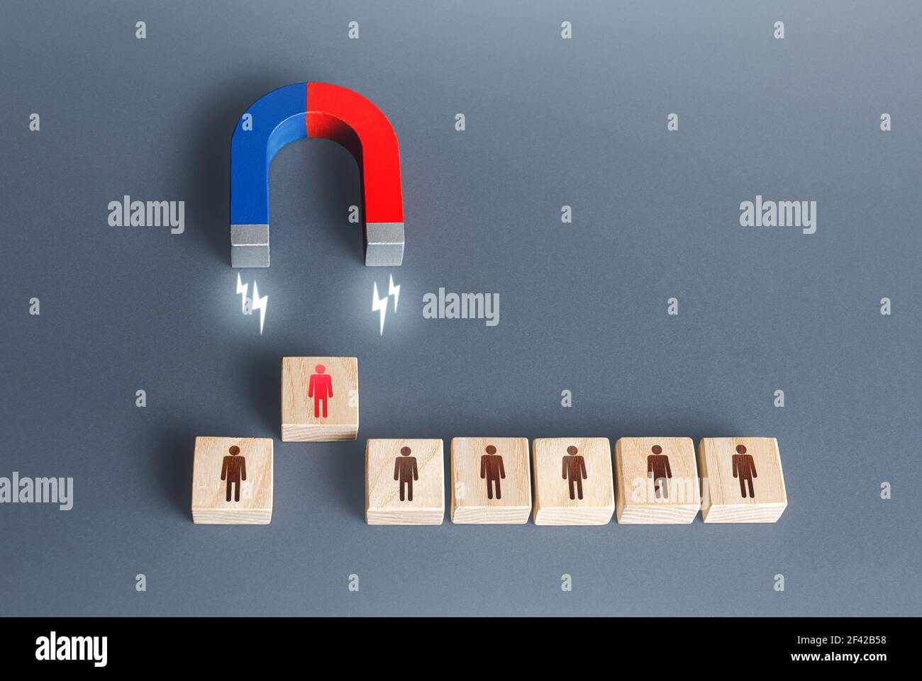 The magnet selects one person from the row. Finding the best recruiting candidate. Hiring and staffing. Human resources. Search for the right person. Stock Photo