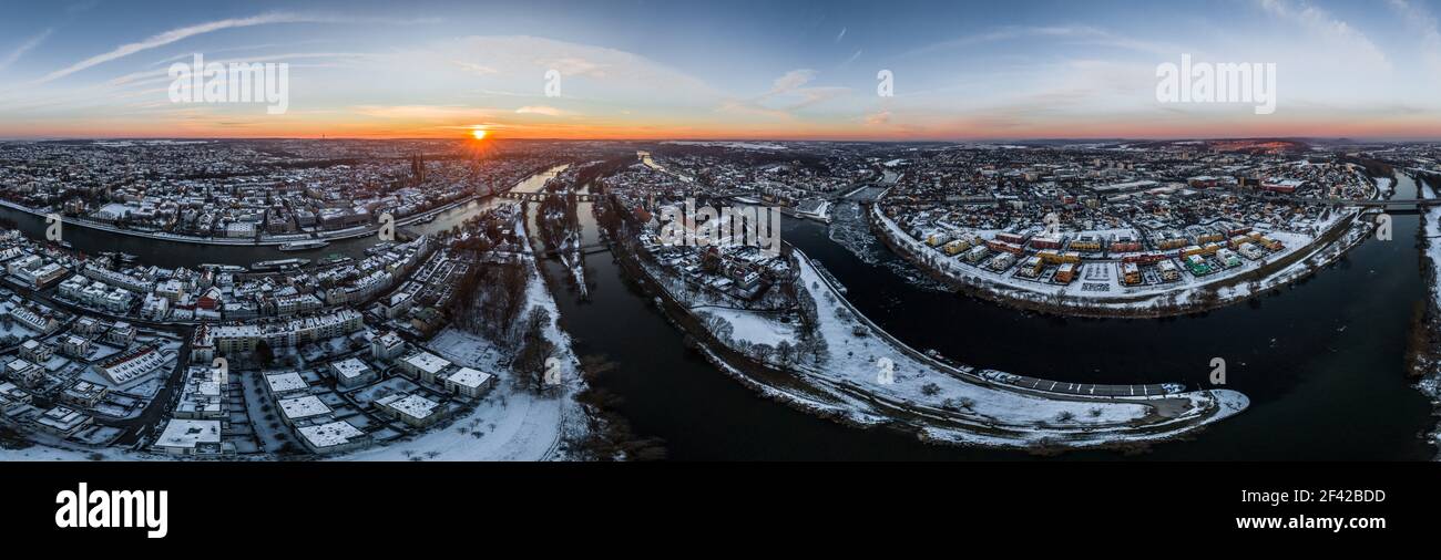 Panorama of Regensburg city in Bavaria with the river Danube the cathedral and the stone bridge in winter with ice and snow at sunset, Germany Stock Photo