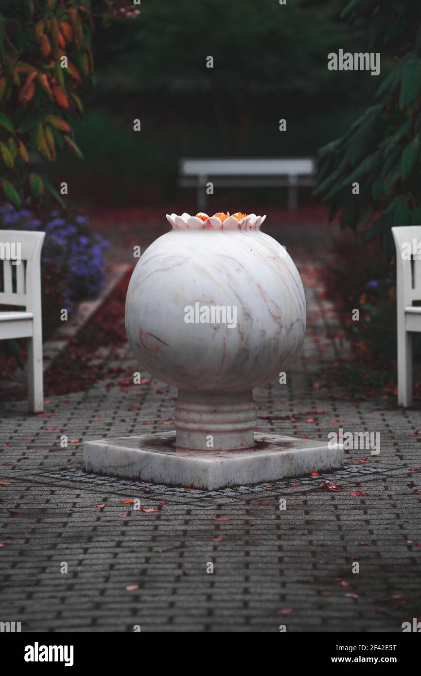 A white marble round vase with flowers on a concrete surface Stock