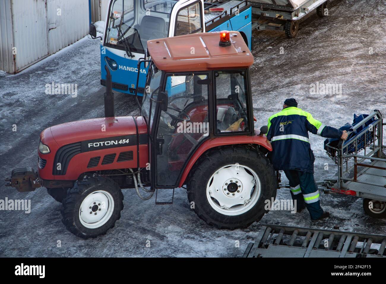 BORYSPIL, UKRAINE, NOV 28 2018, A ground staff of the airport manipulate with trolley for connect at tractor. Stock Photo
