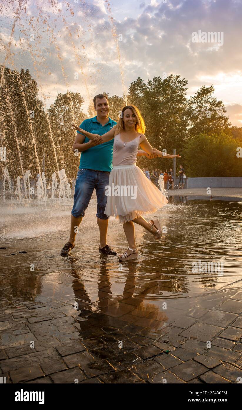 Dnepropetrovsk, Ukraine - 08.20.2017: Joyful townspeople dance on the square in the city at sunset. A couple of young people are dancing under the fou Stock Photo