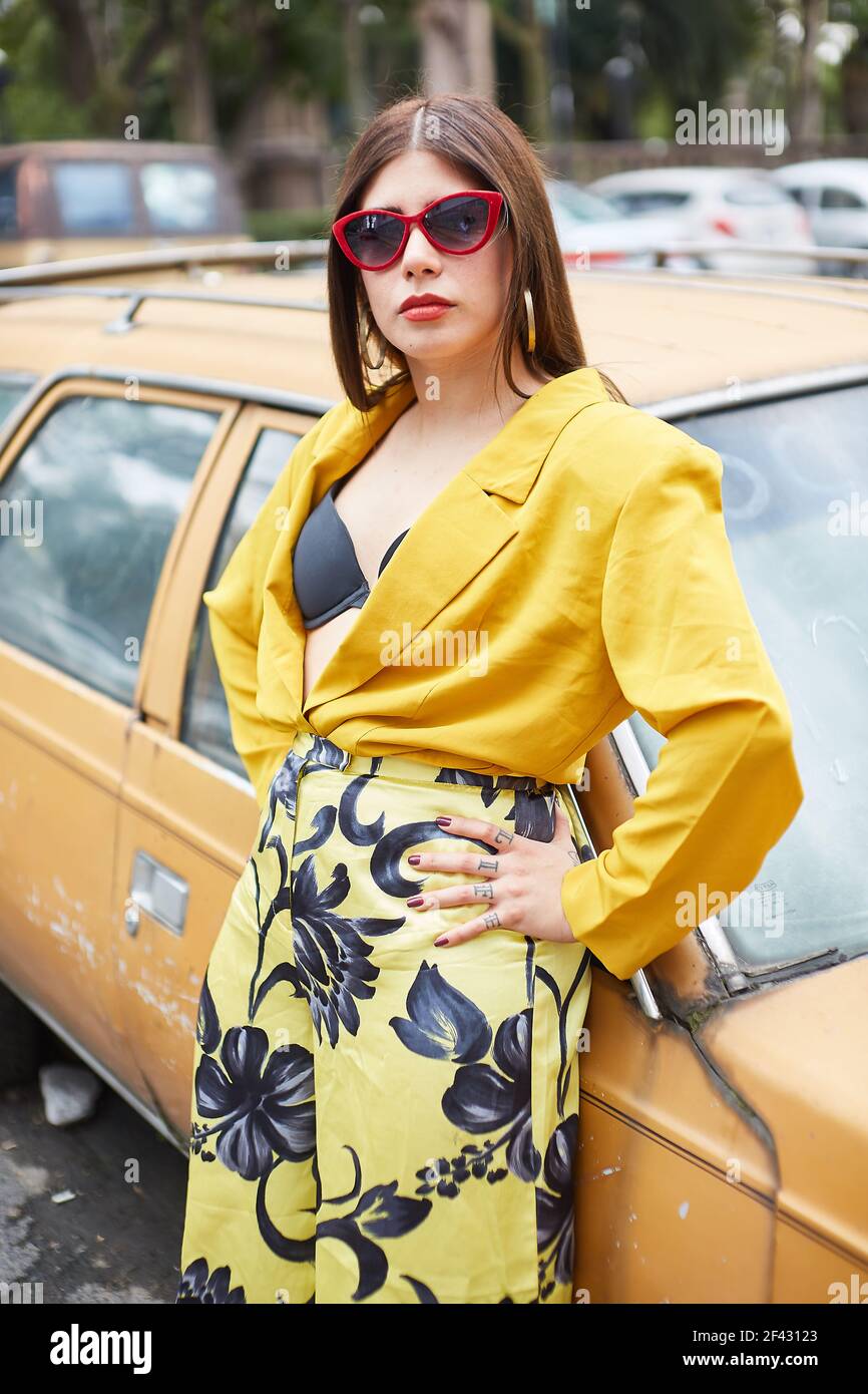 confident young woman leaning on a car and looking at the car Stock Photo