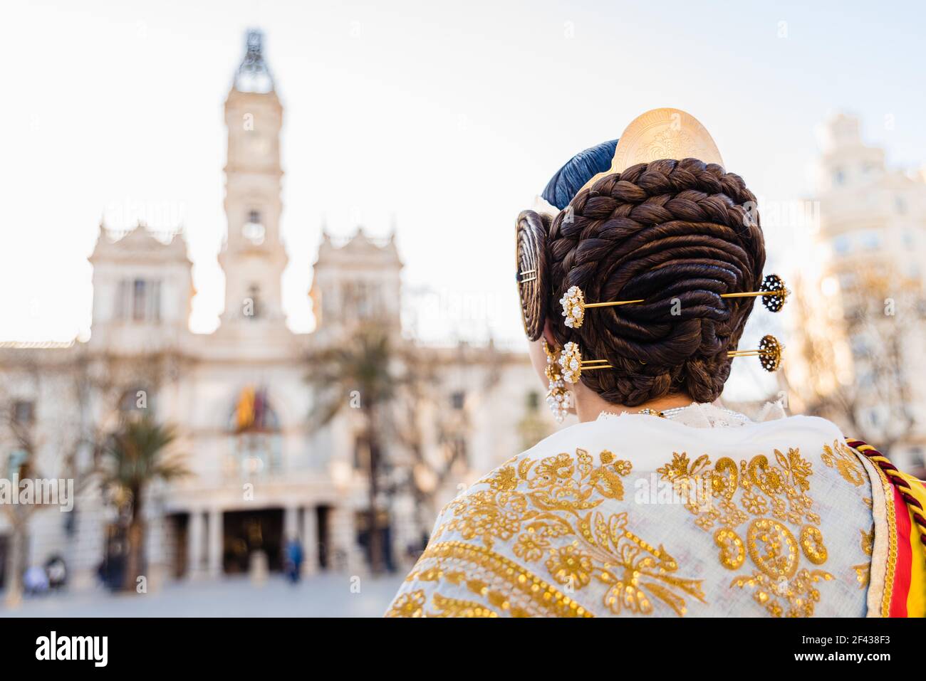 Woman dressed as a Fallera with her back turned, observes the facade of ...