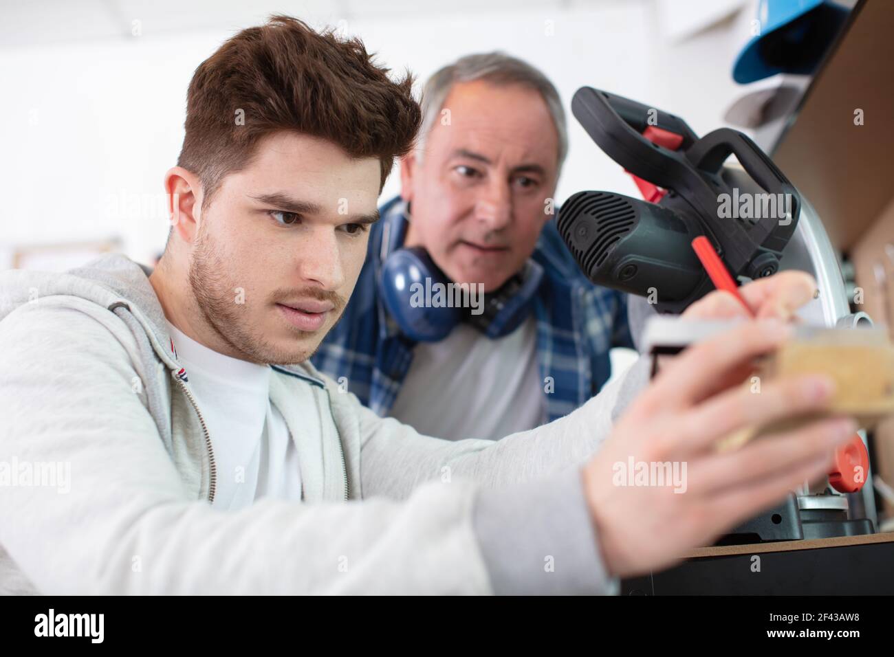student and teacher in carpentry class using circular saw Stock Photo