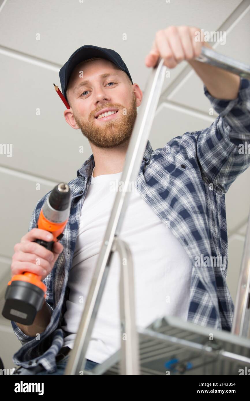 handsome young builder installing light on the ceiling Stock Photo