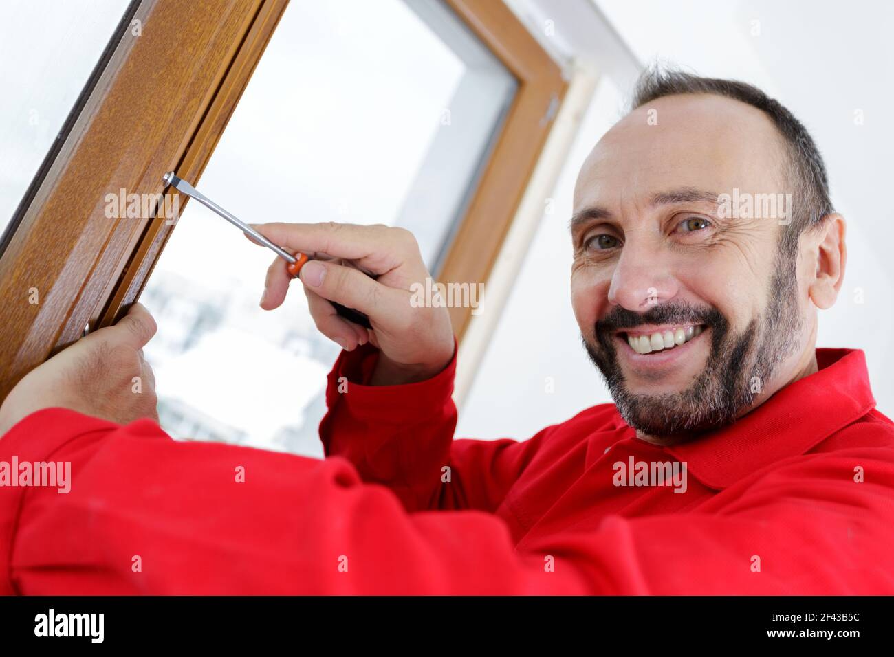 happy man installing blinds with screwdriver Stock Photo