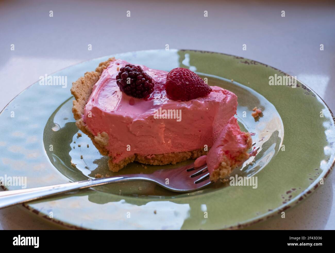 Slice of strawberry chiffon pie with fruit pieces on top. Graham cracker crust. Made with strawberry koolade flavoring. Stock Photo